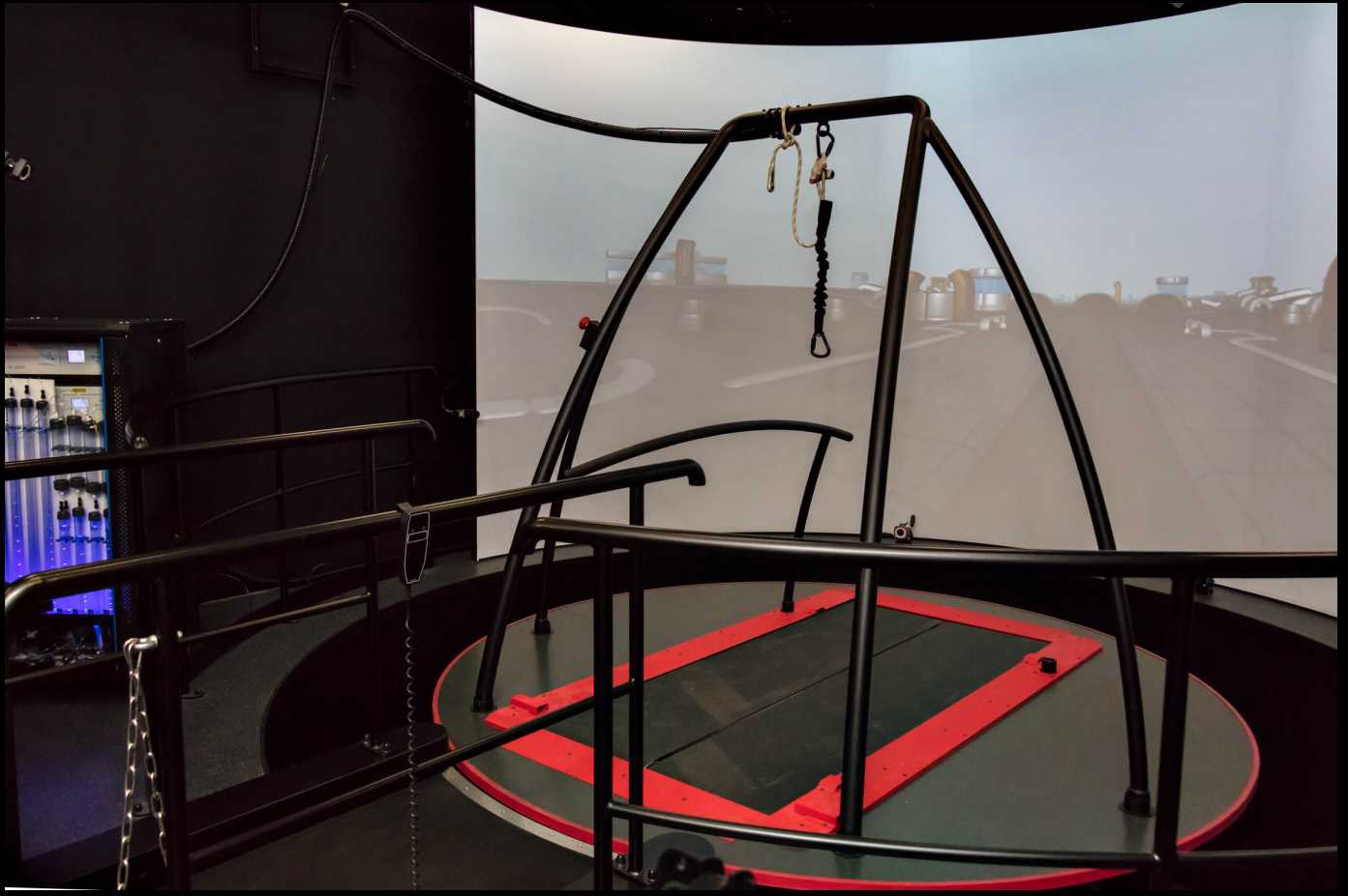 Figure: The Caren system comprising a dual belt treadmill, build on a movable platform, surrounded by a 180° semi-cylindric screen where a virtual environment is projected on. Figure: The Caren system comprising a dual belt treadmill, build on a movable platform, surrounded by a 180° semi-cylindric screen where a virtual environment is projected on.